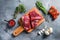 Raw flap steak flank cut with Machete, Skirt Steak, on woods chopping board, with herbs tomatoes peppercorns over grey stone