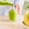 Raw foodism, green smoothie with banana and spinach. Woman pouring detox drink from blender