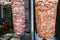 Raw foods for outdoor shawarma - two kinds of meat on vertical grill on kitchen background with vegetables in stainless