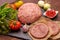 Raw forcemeat with Raw burger cutlet from pork meat on a slate stone plate on a wooden background