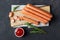 Raw frankfurter sausages with ketchup on cutting board