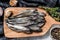 Raw fresh capelin fish on cutting board. Gray background. Top view