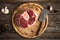 Raw fresh cross cut veal with garlic, pepper and seasonings on wooden cutting board with butcher cleaver.