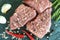 Raw fresh marbled beef meat, seasonings on dark stone cutting board, flat lay