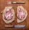 Raw fresh pork steak with old knife and meat fork rustic wooden background top view close up