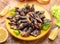 Raw goose barnacles close up on yellow plate on wooden table