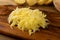 Raw Grated Potato on Wooden Cutting Board Background