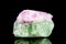Raw green and pink tourmaline mineral stone in front of black background