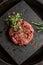Raw ground beef meat steak cutlets with herbs and spices on black board. Restaurant