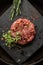 Raw ground beef meat steak cutlets with herbs and spices on black board. Restaurant