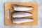 Raw hake fish carcass on a wooden chopping Board. top view Copy space