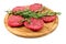 Raw hamburgers with cellophane and rosemary on wooden board