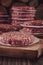 Raw hamburgers on cutting board with hamburger pile background