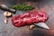 Raw Hanging Tender steak on a butcher knife . Dark background. Top view