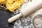 Raw homemade fettucine with flour and rolling pin