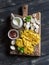 Raw ingredients for cooking pasta with mushroom cream sauce - pasta, mushrooms, cream, spices. On rustic wooden board