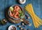 Raw ingredients for cooking - prawns and spaghetti on a wooden background, top view.