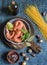 Raw ingredients for cooking - prawns and spaghetti on a wooden background, top view.