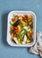 Raw ingredients for lunch - fresh chopped vegetables in the pan on a blue background, top view.