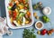 Raw ingredients for lunch - fresh chopped vegetables in the pan on a blue background, top view.