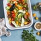 Raw ingredients for lunch - fresh chopped vegetables in the pan on a blue background, top view.