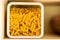 Raw italian macaroni pasta inside clear storage container in kitchen shelf