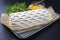 Raw Kasseler pork steak as piece in puff pastry and egg yolks on a griddle with herbs on a black board