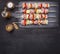 Raw kebabs with pork, vegetables and fruit on vintage cutting board with spices wooden rustic background top view close up plac