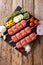 raw kofta, kofte kebab from minced meat on skewers with ingredients and vegetables close-up. Vertical top view