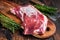 Raw lamb or goat shoulder meat on the bone on a wooden butcher cutting board with cleaver. Dark wooden background. Top