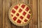 Raw lattice round cake with strawberry jam in metal form on wood