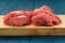 Raw lean meat cuts on wooden board on deep blue background