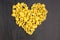 Raw macaroni - conchiglie paste shells in the shape of a heart on a dark background
