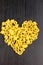 Raw macaroni - conchiglie paste shells in the shape of a heart on a dark background