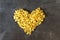 Raw macaroni - pasta Conchiglie. In the middle of the empty space in the shape of a heart on a dark concrete background.