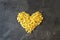 Raw macaroni - pasta Conchiglie. In the middle of the empty space in the shape of a heart on a dark concrete background.