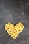 Raw macaroni - pasta Conchiglie. In the middle of the empty space in the shape of a heart on a dark concrete background.