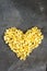 Raw macaroni - pasta Conchiglie. In the middle of the empty space in the shape of a heart on a dark concrete background.