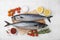 Raw mackerel, tomatoes and rosemary on white tiled table, flat lay