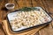 Raw Manti Dumpling with meat in tray with herbs and spices. Wooden background. Top view