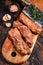 Raw Marinated skirt steaks in bbq sauce on a wooden cutting board with herbs. Dark wooden background. Top view