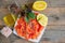 Raw marinated trout fillet and salmon slices with lemon slices on a white plate. Wooden background. The view from the top