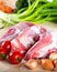 Raw meat beef slices on a wooden chopping board with fresh organic vegetables, onion, garlic, spices, peppercorn, rosemary, sea sa