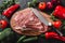 Raw meat, beef steak on cutting board with knife on black background with ingredients for cooking.