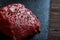 Raw meat beef steaks on black slate board with spices and rosemary over wooden background, copy space