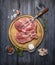 Raw meat on an board with a napkin, fork, sauce, salt and pepper on rustic wooden background