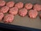 Raw meat cutlets on parchment paper in a baking sheet