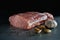 Raw meat on a gray background. A large piece of fresh mouth-watering meat with garlic and pepper. Culinary concept