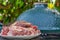 Raw meat in a plate, cut into pieces, seasoned and ready to grill, outdoors, against the backdrop of a ceramic barbecue