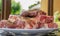 Raw meat in a plate, cut into pieces, seasoned and ready to grill, outdoors. Close-up, small depth of field